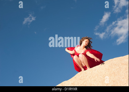 Femme dans une robe rouge sur un paysage haut en pierre avec Big Sky. Banque D'Images