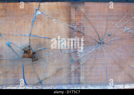 Verre de sécurité cassé avec des fissures qui rayonnent vers l'extérieur dans un trou et formation web spiders Banque D'Images