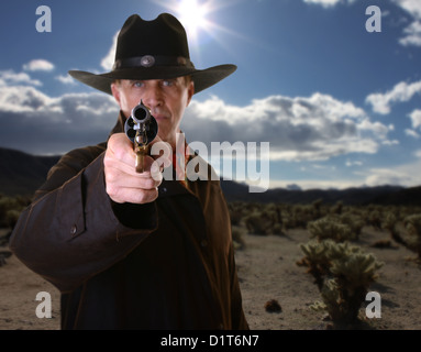 Cowboy pointing gun avec focus sélectif sur les armes contre l'arrière-plan du désert Banque D'Images