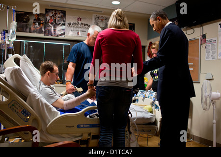 Le président américain Barack Obama prie avec un membre du service blessé et sa famille lors d'une visite de Walter Reed National Military Medical Center le 28 juin 2012 à Bethesda, MD. Banque D'Images