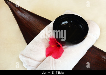 Rolled up towel blanc avec les fleurs rouges Banque D'Images