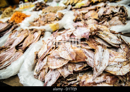 Fruits de mer séchés au marché du matin Luang Prabang Laos // LUANG PRABANG, Laos — Un vendeur présente des fruits de mer séchés et salés, y compris des calmars, des crevettes et du poisson au marché du matin. Ces conserves servent d'ingrédients essentiels dans la cuisine traditionnelle lao, fournissant des sources de protéines qui peuvent être stockées sans réfrigération dans le climat tropical. Les techniques de conservation de séchage et de salage permettent le stockage et le transport à long terme des produits de la mer des zones côtières vers les marchés intérieurs du Laos. Le marché du matin de Luang Prabang sert de plaque tournante centrale pour le commerce local, où Banque D'Images