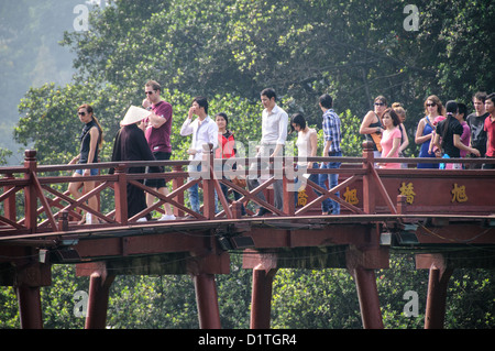 HANOI, Vietnam — les touristes traversent le pont Huc (pont du soleil du matin). Le pont en bois peint en rouge relie la rive nord du lac à l'île de Jade et au temple de la montagne de Jade (temple Ngoc son). Banque D'Images