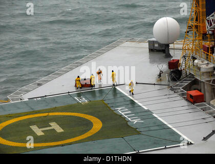 Une équipe de sauvetage à bord de Royal Dutch Shell, unité de forage Kulluk conique déplace un système de remorquage d'urgence livrés à l'Kulluk par un U.S. Coast Guard hélicoptère Jayhawk MH-60T 40 milles au sud-ouest de la ville de Kodiak, Alaska, sur la rive de l'île Sitkalidak JAN. 5, 2013.. (U.S. Photo de la Garde côtière par Maître de 1re classe Travis Marsh/libérés) Banque D'Images