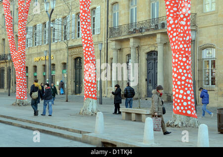 Des piétons se promeuvent devant un hôtel particulier ou une maison de ville Bourgeois et un avion-arbre enveloppé décoré de papier à pois rouge et blanc par l'artiste japonais Yayoi Kusama cours Mirabeau Aix-en-Provence pour l'inauguration de Marseille-Provence 2013 capitale européenne de la culture. Provence France Banque D'Images