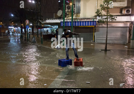 Un migrant africain traversant une rue inondée en un jour de pluie dans le quartier de Neve Shaanan qui est devenu le foyer de l'une des plus grandes populations d'Africains et d'autres migrants dans le sud de tel Aviv Israël Banque D'Images
