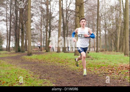 Kent Championnats de cross-country de moins de 17 jeunes garçons s'exécutant sur le chemin du sentier à travers le bois dans le brouillard et les conditions brumeuses Banque D'Images