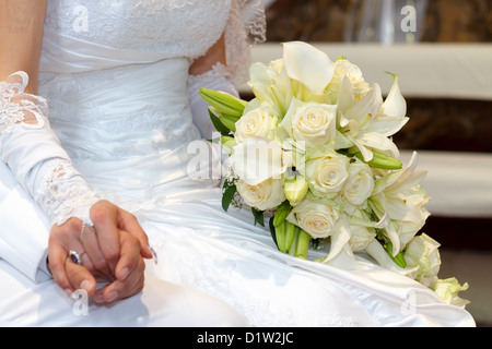 Jour de mariage mariée et se toilette mains avec bouquet de mariage Banque D'Images