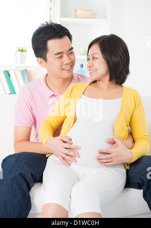 Couple chinois asiatique. Mari et enceinte de 8 mois femme assis sur le canapé Banque D'Images