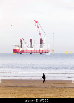 Navire à l'aide d'un cric de levage lourd Aventure MPI Installation de l'éolienne tour en acier à Redcar Wind Farm Janvier 2013 man on beach Banque D'Images