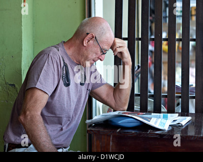 Man reading newspaper. Mâle mature plongé dans le quotidien et de façon réfléchie et contemplative. Banque D'Images