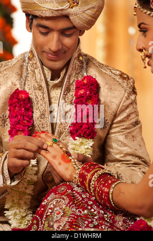 Groom indiens mettant un anneau de mariage sur une mariée Banque D'Images