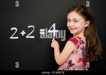 Jeune fille portant une robe rouge écrit sommes mathématiques sur un tableau noir Banque D'Images