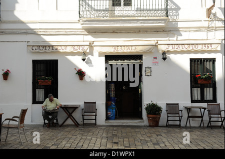 La lecture de l'homme en face de bar en Vejer de la Frontera, l'un des villages blancs ou les villages blancs d'Andalousie, Espagne Banque D'Images