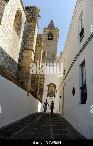Un couple marche main dans la main aux côtés de Divino Salvador Église, Vejer de la Frontera, Andalousie, Espagne Banque D'Images