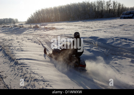 L'homme sur une motoneige traversant le champs dans les régions rurales de la Saskatchewan Canada Forget Banque D'Images