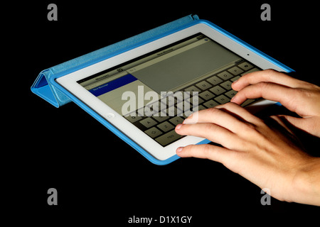 Un iPad avec écran Retina blanc dans un étui bleu sur un fond noir avec une jeune femme en train de rédiger un message Banque D'Images