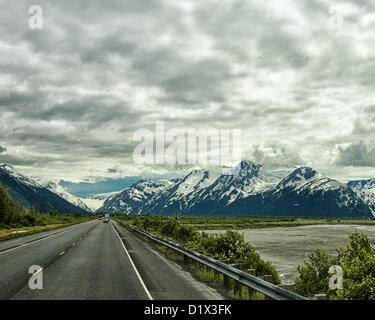 29 juin 2012 - péninsule de Kenai, Alaska, Etats-Unis - conduite au sud, pittoresque Seward Highway longe la base de la Chugach Mountains [gauche] et offre des vues spectaculaires sur les glaciers, montagnes aux montagnes Kenai encadrée par les formations de nuages spectaculaires. Ils s'élèvent au loin au-dessus de Turnagain Arm, à marée basse, ses eaux juste couvrant la baie. Une forêt nationale désignée Scenic Byway, un All-American Road et un Scenic Byway, l'ALASKA Seward Highway exécute 127 miles [204 km] de mouillage à Seward à travers la péninsule Kenai Chugach State Park, la Forêt Nationale de Chugach et, une vitrine des produits de beau Banque D'Images