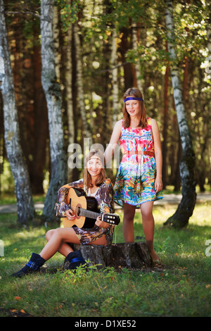 Filles Hippie avec guitare assis sur la souche Banque D'Images