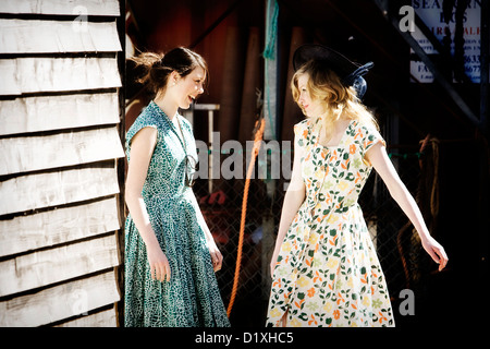 Deux jeunes femmes brunette portant des robes vintage print rire ensemble dans une cabane de plage location Banque D'Images