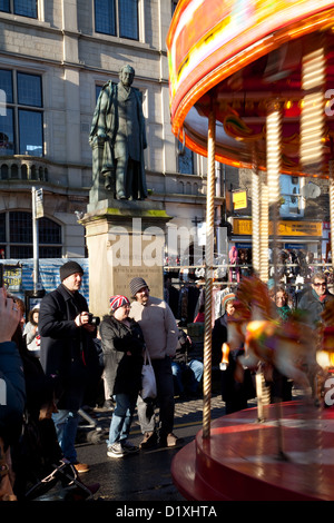 Carrousel pour enfants et statue de Sir Mathew Wilson, vue sur le Fayre de Noël et le festival festif Dickensien, Skipton High Street, Yorkshire, Royaume-Uni Banque D'Images