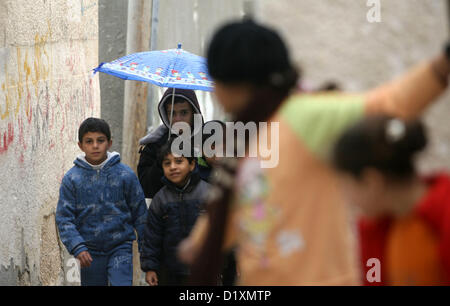 8 janvier 2013 - Rafah, bande de Gaza, territoire palestinien - enfants palestiniens tenir un parapluie promenades en face de maisons dans le camp de réfugiés de Rafah dans le sud de la bande de Gaza 08 Janvier, 2013. Une tempête a frappé la côte est de la Méditerranée et de fortes pluies avec les inondations sont prévues en Israël et dans les territoires palestiniens pour les prochains jours, avec une bonne chance de la neige qui tombe en haute altitude (crédit Image : © Eyad Al Baba/APA Images/ZUMAPRESS.com) Banque D'Images