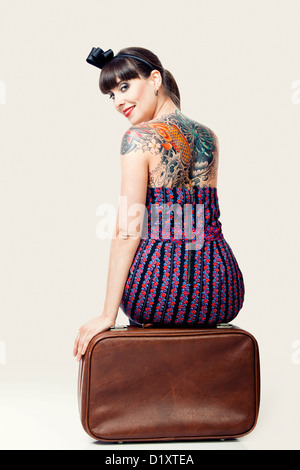 Portrait d'une belle femme avec un style vintage assis sur les bagages Banque D'Images