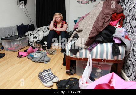 Déprimé girl sitting on lit dans sa chambre en désordre Banque D'Images