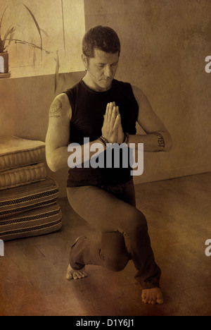 L'homme à une jambe squat profond eagle holding ses mains en prière. Banque D'Images