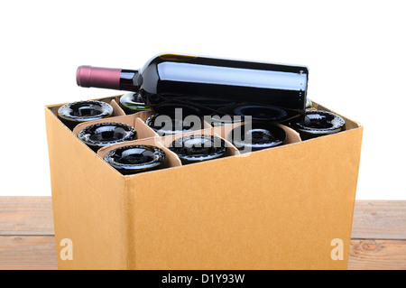 Libre d'une caisse de vin avec un flacon reposant sur le dessus. Cas est assis sur une table en bois avec un fond blanc. Banque D'Images