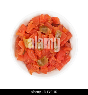 Vue de dessus d'un petit bol rempli de dés de tomates garnies de poivrons verts sur fond blanc. Banque D'Images