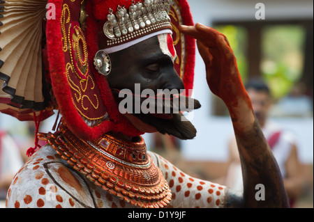 Artiste Theyyam en costume traditionnel et make-up offre une prière aux Dieux lors d'un festival près du village de Thottada. Banque D'Images