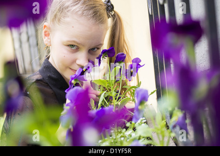 L'inhalation de jeune fille belle fleurs bleu fenêtre près de grill Banque D'Images