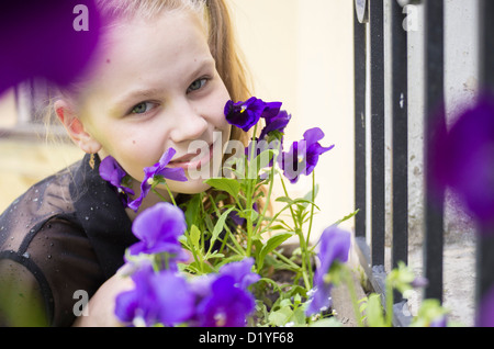 L'inhalation de jeune fille belle fleurs bleu fenêtre près de grill Banque D'Images