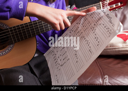 Lecture d'écolière des accords sur sa guitare. Banque D'Images