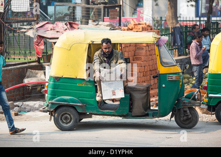 Conducteur de pousse-pousse de lire le journal dans Delhi, Inde Banque D'Images