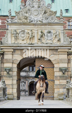 Frederiksborger avec rider en costume historique trottant à travers une porte de Frederiksborg Palace, Danmark Banque D'Images