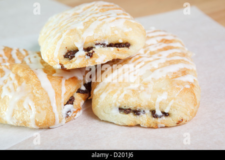 Trois golden et feuilletée remplie de chocolat glacé, les croissants sur un moule de papier ciré, et des carrés de chocolat et patisseries. Banque D'Images