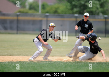 Le coureur de la base de baseball glisse en toute sécurité avec une seconde base tandis que l'arrêt court opposé attend le jet en retard. ÉTATS-UNIS. Banque D'Images