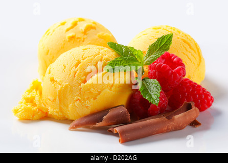 Trois boules de glace jaune avec les framboises et copeaux de chocolat Banque D'Images