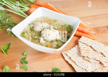 Une seule portion de la matsa cachère ball soupe sur une table en bois garnie de carottes fraîches azyme et crackers Banque D'Images