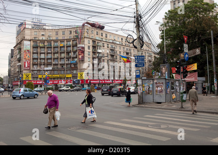 Bucarest, Roumanie, la Place Romana téléphone typique avec l'enchevêtrement de câbles et les piétons de traverser une route Banque D'Images