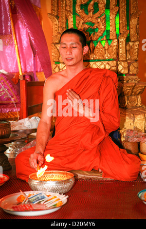 Un moine bouddhiste effectuant les Su Khwan ou Baci cérémonie à Wat Si Muang, Vientiane, Laos, Indochine. Banque D'Images