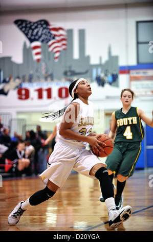 Le sport féminin de basket-ball player remplissant un lecteur de base avec le panier dans ses yeux au cours de l'école secondaire jeu. USA. Banque D'Images