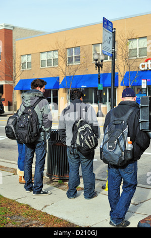 Les étudiants de Chicago Illinois USA d'attente à un arrêt d'autobus sur Taylor Street à Chicago quartier la Petite Italie Banque D'Images