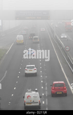 White Cart Viaduct, Arkleston, Renfrewshire, Écosse, Royaume-Uni, jeudi 10 janvier 2013. Trafic traversant le brouillard sur l'autoroute M8 avec attention brouillard affiché sur un panneau LED du statif au-dessus Banque D'Images