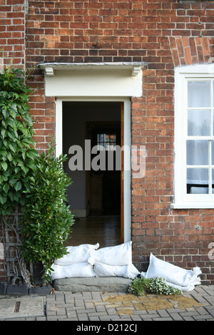 Chambre cottage en brique anglais préparé pour les inondations avec des sacs de sable à l'extérieur c'est la porte avant. Une Ivy Bush pousse à côté. Banque D'Images