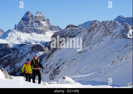 Jeune femme et jeune homme avec croissant à skis ski Corno d'Angolo, Tre Cime di Lavaredo en arrière-plan, Corno d'Angolo Banque D'Images