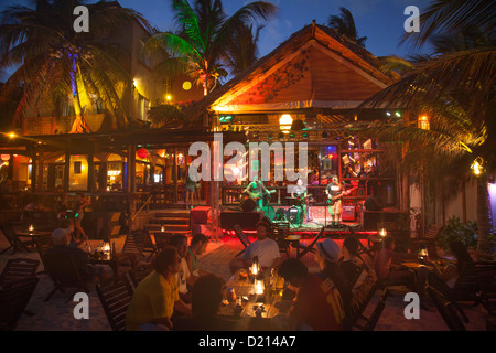 Les gens assis à l'extérieur de l'écoute d'un groupe jouant de la musique live au bar de plage et restaurant Fusion, Playa del Carmen, Riviera Banque D'Images