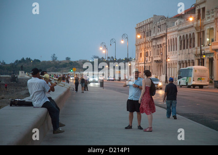 Musiciens de rue sur la mer Malecon dur en tant que touristes passent au crépuscule, La Havane, La Havane, Cuba, Caraïbes Banque D'Images